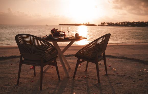 Zwei Stühle mit einem gedeckten Tisch am Strand 