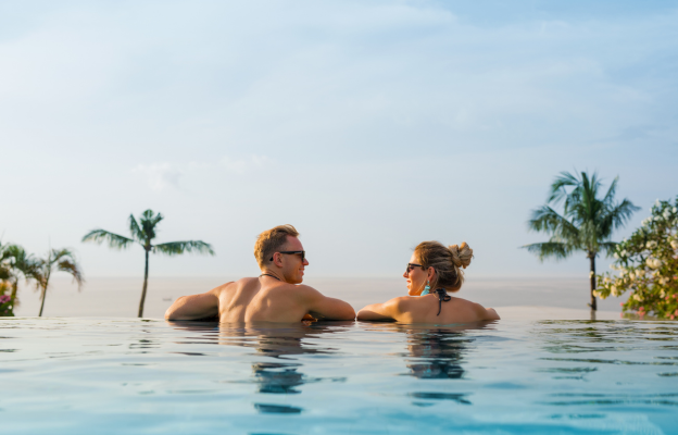 Pärchen entspannt im Infinity Pool mit Palmen im Hintergrund
