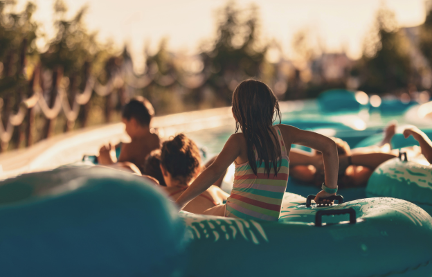 Kinder auf sitzen auf im Wasserpark auf einem Schwimmreifen und wollen eine Rutsche herunterfahren