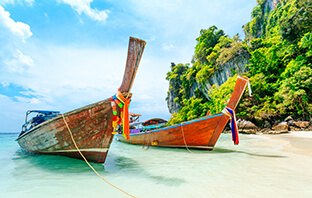 Zwei Longtail Boote liegen am traumhaften Strand in Thailand
