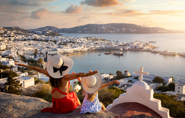 Mutter sitzt mit Tochter an Aussichtspunkt in Santorini