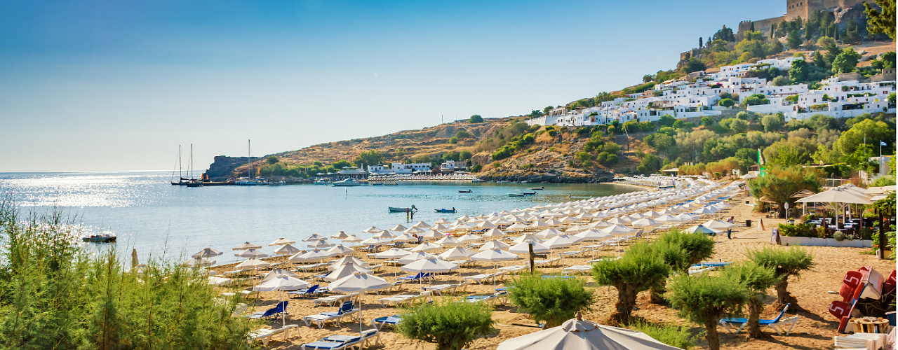 Griechisches Hotel am Strand mit vielen Liegen und Sonnenschrimen