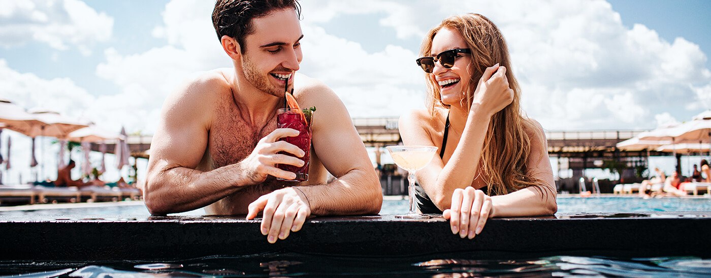 Paar sitzt am Rand eines Pools und genießt den Urlaub mit den Hotel Angeboten von BILLA Reisen