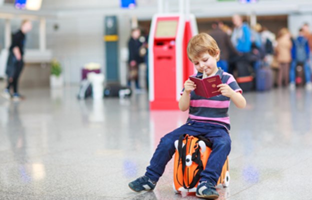 Bub auf Kinderkoffer mit Reisepass