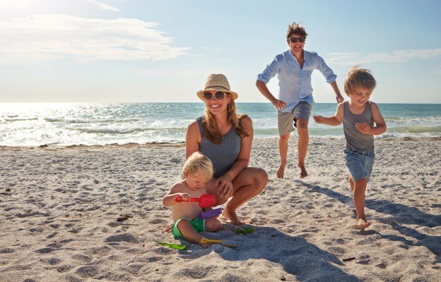 Glückliche Familie spielt am Strand im Familienurlaub