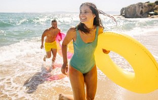 Ein Pärchen läuft glücklich am Strand entlang und genießt den günstigen Urlaub