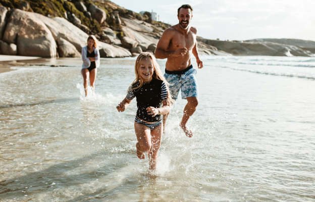 Familie spielt am Meer und Töchter und Vater spielen herum