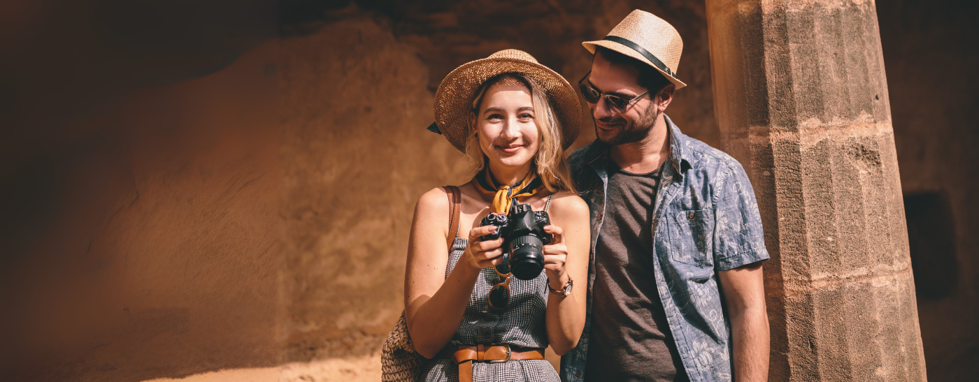 Paar steht mit Kamera und Strohhüten in einer antiken Sehenswürdigkeit und genießt die Rundreise