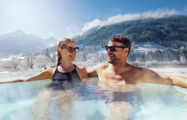 Paar sitzt im Pool beim Wellness Urlaub