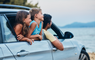 Familie sitzt im Auto und fährt zu ihrem gebuchten Urlaub 