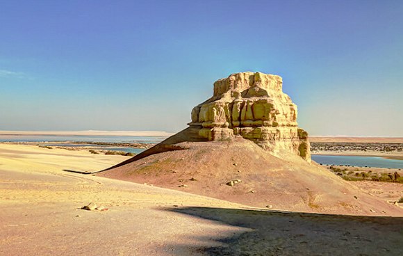 Wadi El Rayan - Wüste mit Fels und See im Hintergrund