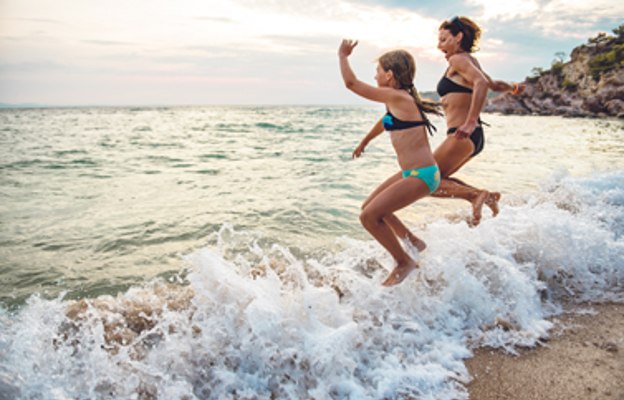 Mutter und Tochter springen am Strand