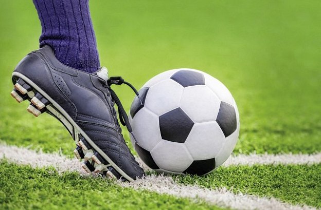 Ein Fuß tritt einen Ball auf einem Fußballfeld in der Nahaufnahme