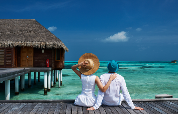 Paar sitzt am Pier bei einem Wasserbungalow auf den Malediven