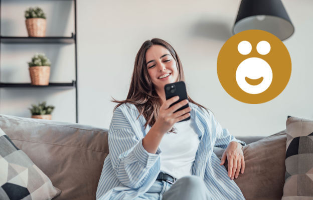 Frau sitzt auf der Couch und freut sich mit ihrem Handy in der Hand über 10.000 Ös 