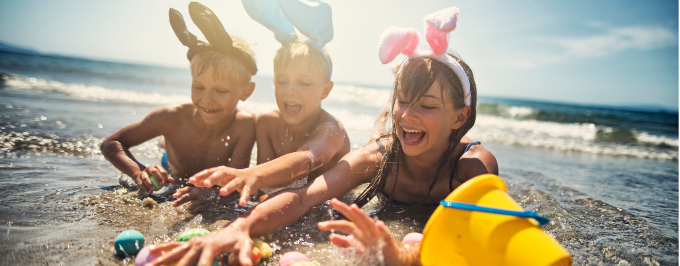 Kinder mit Osterhasen Ohren liegen am Strand