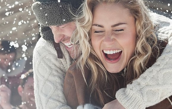 Paar steht im Schnee und genießt ihren Winterurlaub