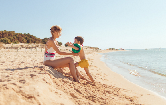 Mutter und Sohn sind am Strand direkt am Meer und genießen das schöne Wetter