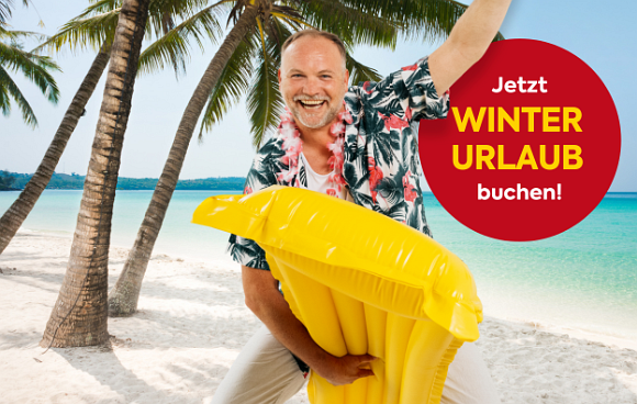 Thomas Stipsits steht am Strand mit einer Luftmatratze als Schlitten und genießt seinen Winterurlaub